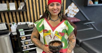 Local tattoo artist holds wears ceremonial dress and holds vessel for burning cleansing items.